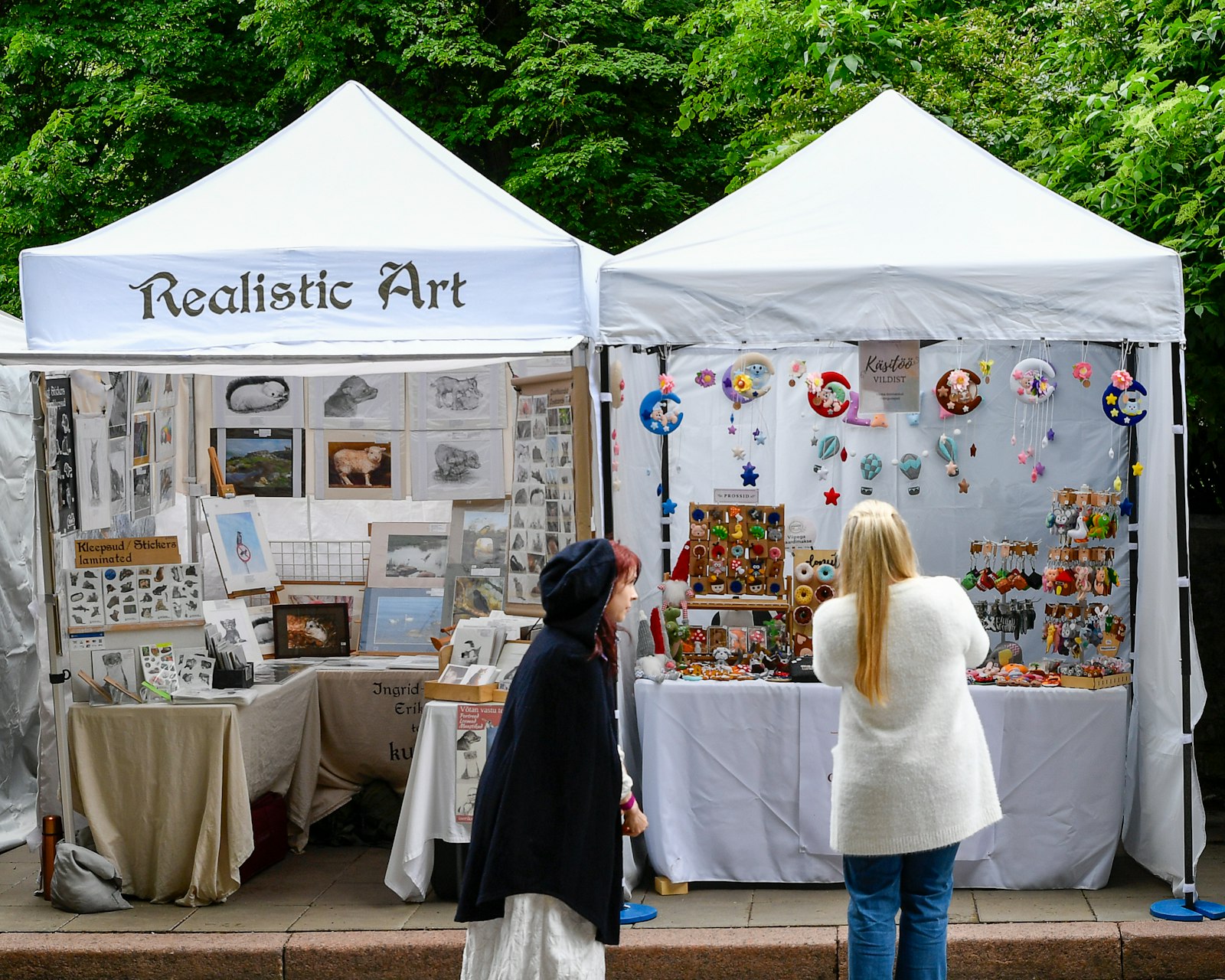 Shoppers browsing an artist booth at an outdoor market