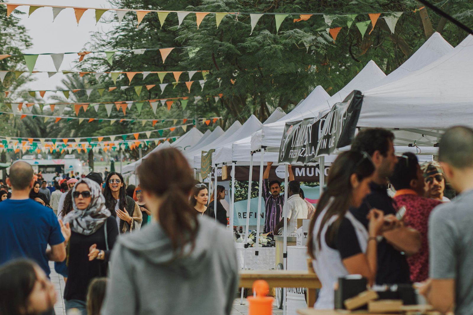 Crowd walking between vendor tents at an outdoor festival
